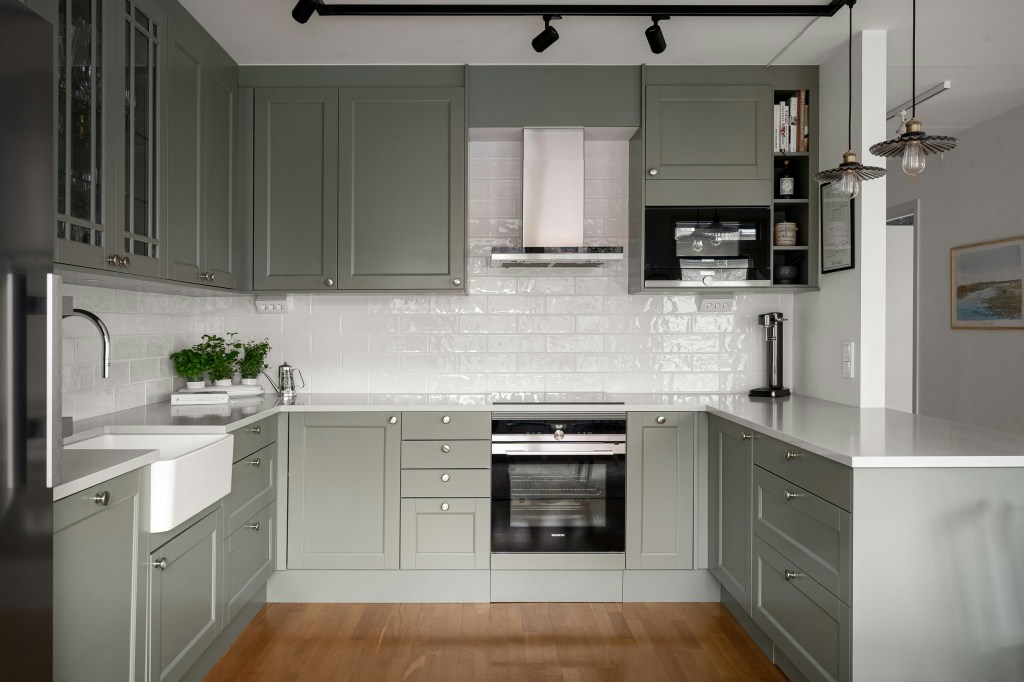 Nowoczesna jasna kuchnia z pastelową zieloną zabudową i chromowanymi akcentami, modny design 2025